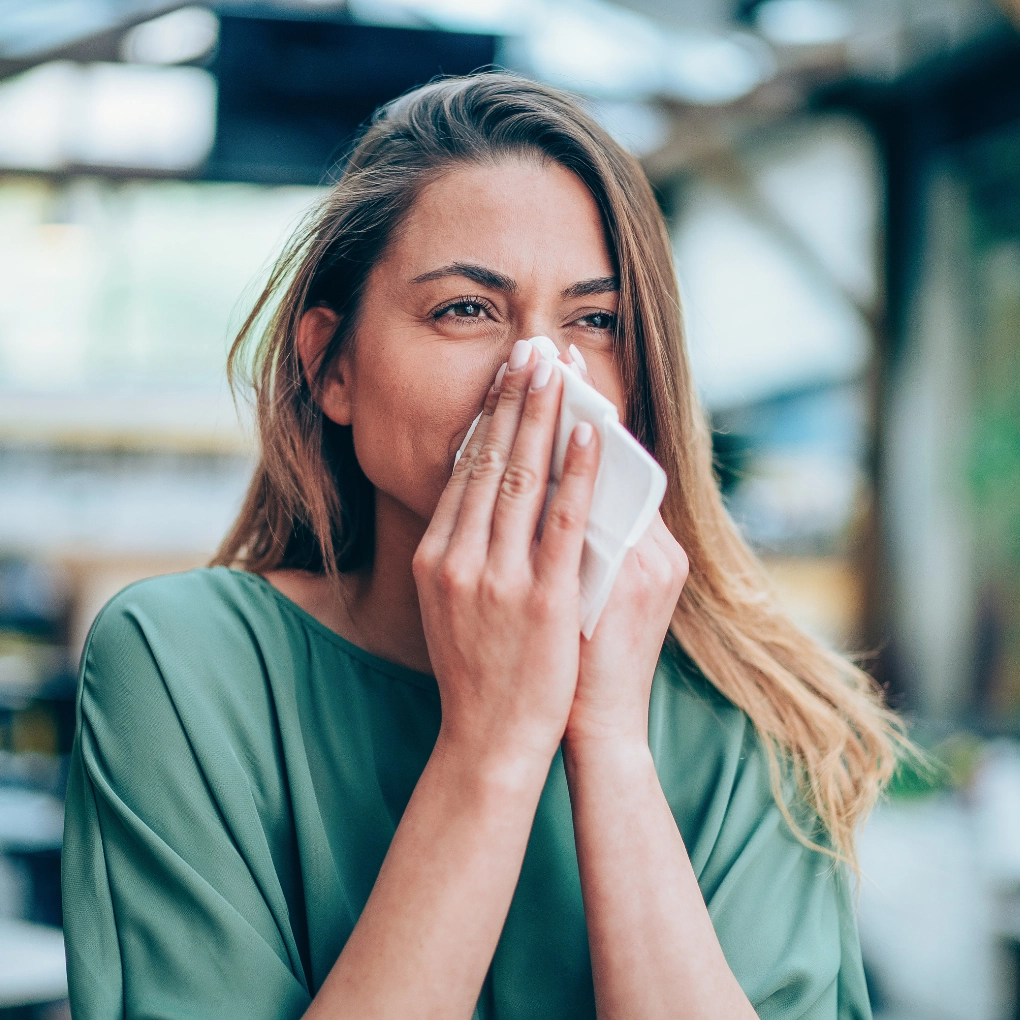 Woman cleaning her nose with a handkerchief due to cold and allergies.
