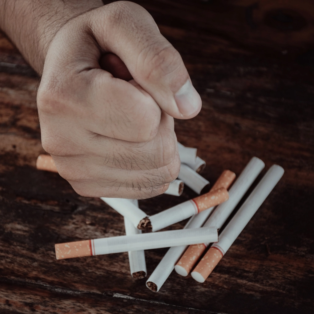 A hand holding a fist over a pile of cigarettes.
